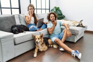 young-couple-relaxing-at-home-with-dogs-in-the-living-room-touching-painful-sore-throats